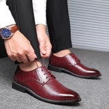 Scarpe eleganti da uomo in pelle marrone, indossate con pantaloni neri. Uomo allaccia i lacci, orologio al polso. Moda maschile, calzature formali.