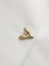 Gold button detail on white V-neck top, close-up