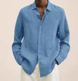 Camicia di lino azzurra da uomo, maniche lunghe, abbinata a pantaloni bianchi. Moda estiva elegante e casual.