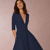 Abito elegante blu scuro con scollo a V e maniche a tre quarti, indossato da una donna su sfondo neutro. Moda femminile, abbigliamento chic.