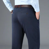 Pantaloni eleganti uomo blu scuro, tasche posteriori, cintura marrone, camicia azzurra. Abbigliamento formale maschile, moda business.