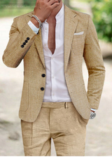 Uomo in elegante abito beige, camicia bianca aperta, orologio e bracciale argento, in posa all'aperto. Moda maschile, stile sofisticato.